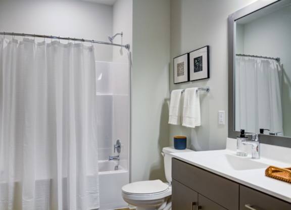 A white bathroom with a toilet, sink, and shower curtain.