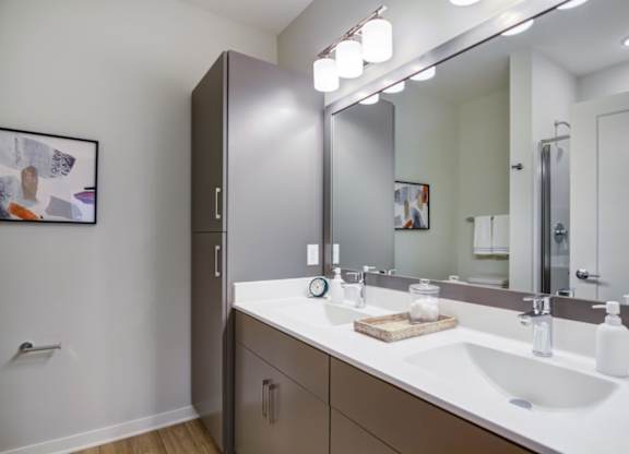 A bathroom with a white sink and a brown cabinet.