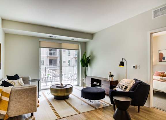 A living room with a grey couch, a black chair, and a yellow throw blanket.