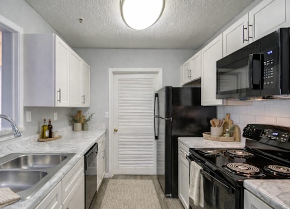 A kitchen with black appliances and white cabinets.