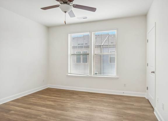 an empty room with a ceiling fan and a window