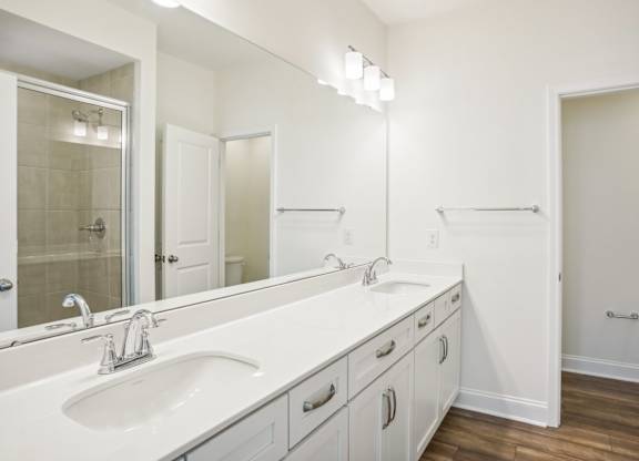 a white bathroom with two sinks and a mirror