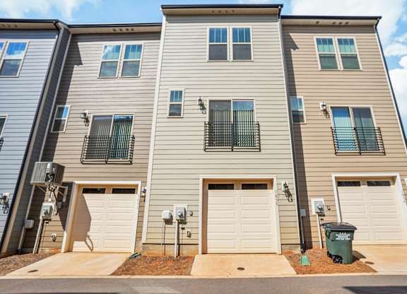 an apartment building with three garage doors and a sidewalk