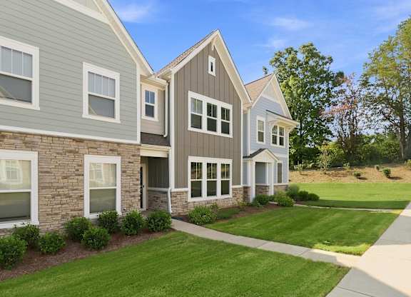 A row of houses with a green lawn in front.