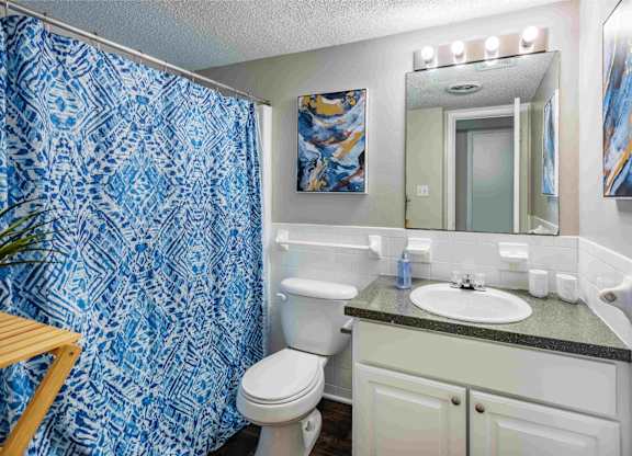 A bathroom with a toilet, sink, and shower curtain.