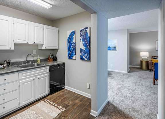 A kitchen with white cabinets and a blue painting on the wall.