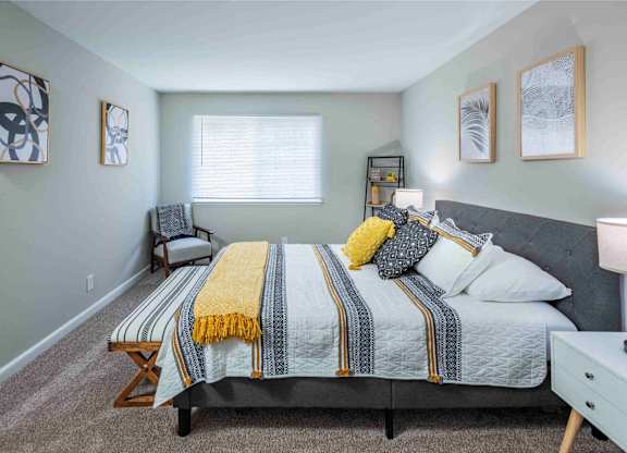 A bedroom with a bed, nightstand, and chair.