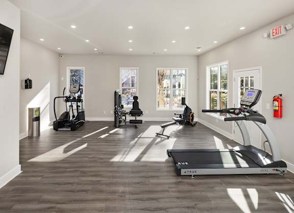 A gym with treadmills, elliptical machines, and a fire extinguisher.