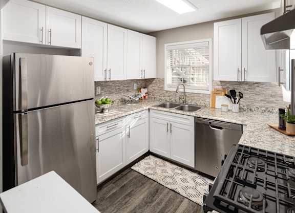 A modern kitchen with a stainless steel refrigerator and black stove top.