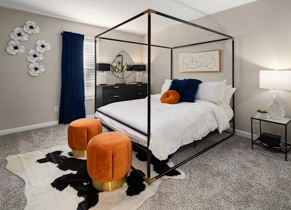 A bedroom with a four poster bed and a cowhide rug.