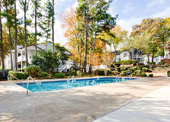 A swimming pool surrounded by trees in a residential area.