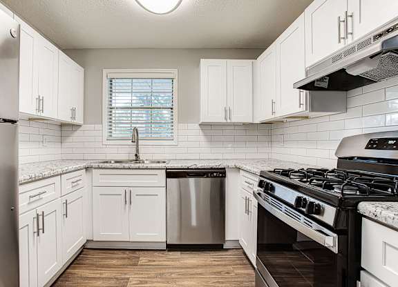 A kitchen with white cabinets and a black stove top oven.