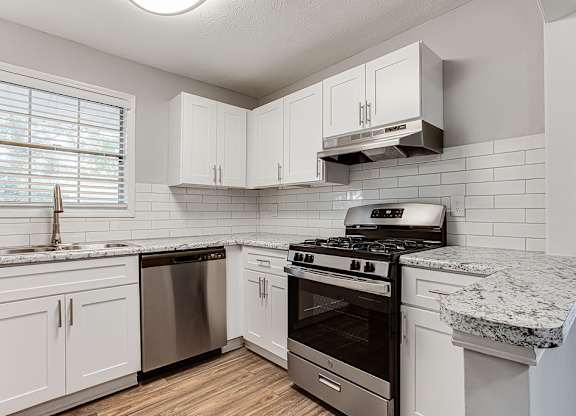A kitchen with a stove, oven, and cabinets.