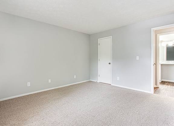 A room with a carpeted floor and two doors.