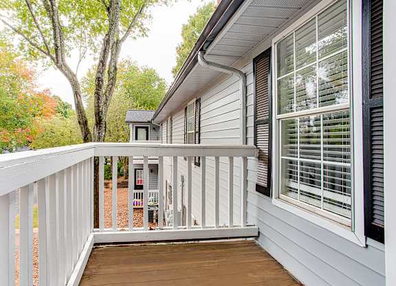 A white house with a deck and a small shed in the back.