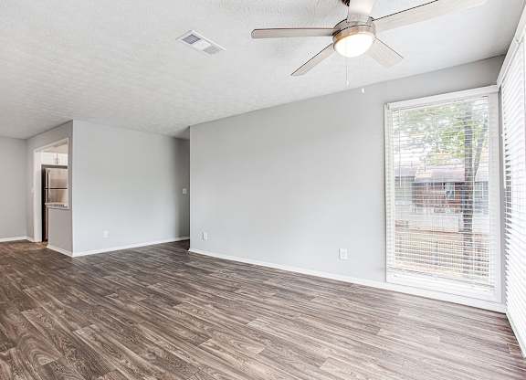 A room with a ceiling fan and wooden flooring.