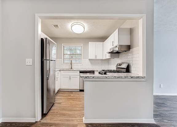 A kitchen with white cabinets and a refrigerator.