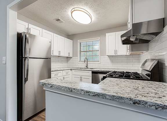 A kitchen with a refrigerator, stove, and white cabinets.