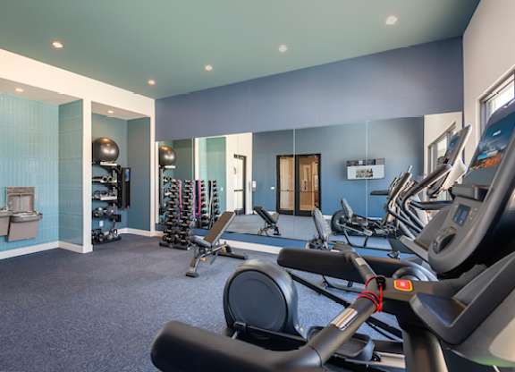 A gym with a variety of exercise equipment including treadmills, stationary bikes, and weight machines.