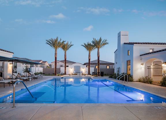 A swimming pool surrounded by palm trees and a building in the background.