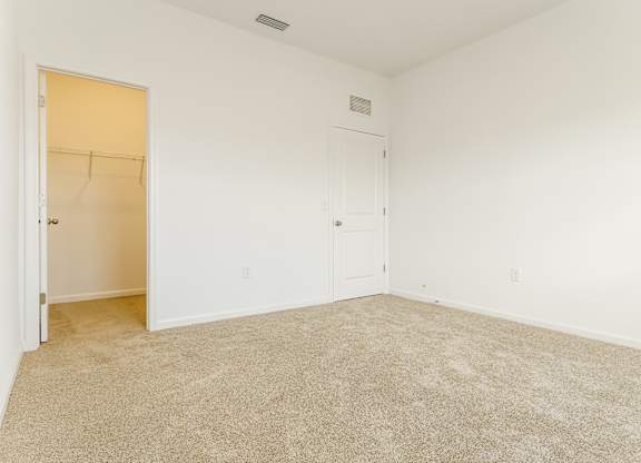 A room with a carpeted floor and a door on the left.