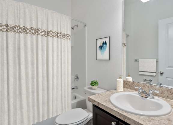 A bathroom with a white toilet, a sink, and a shower curtain.