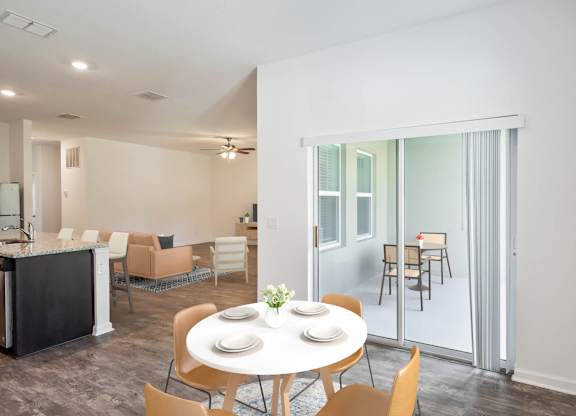 A dining room with a table set for two and chairs around it.