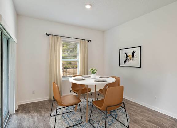 A dining room with a table set for two and a framed picture of a bird on the wall.