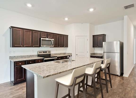 A kitchen with brown cabinets and a granite countertop.