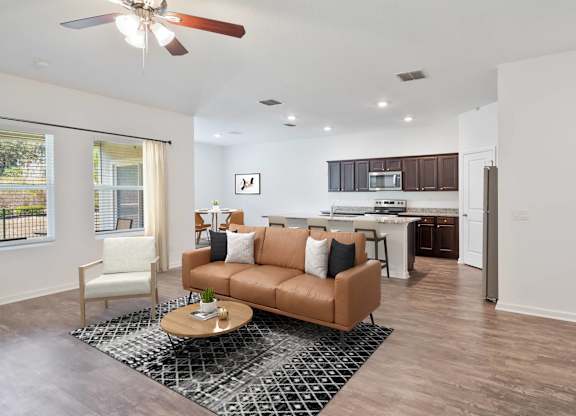A living room with a brown couch and a ceiling fan.