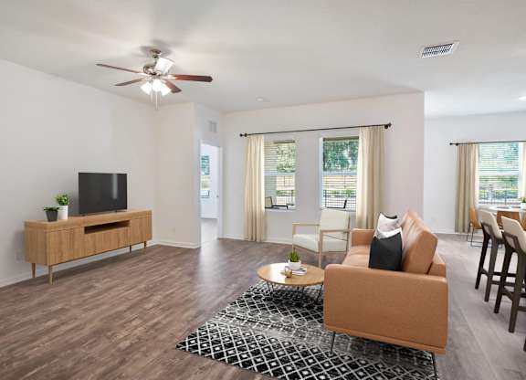 A living room with a brown sofa, a wooden entertainment center, and a ceiling fan.