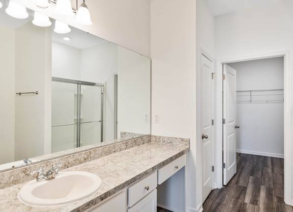 A bathroom with a sink, mirror, and wooden floors.