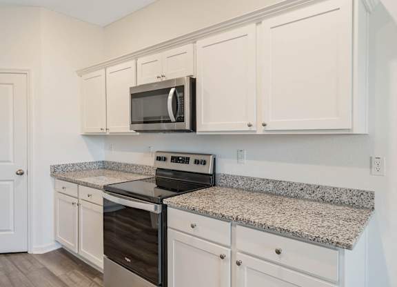 A kitchen with granite countertops and white cabinets.