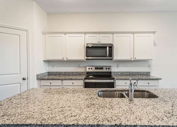A kitchen with granite countertops and white cabinets.