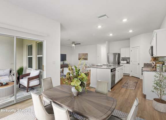 A modern kitchen with white cabinets and a dining table set for two.