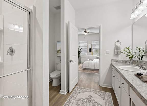 A bathroom with a glass shower door, a toilet, a sink, and a mirror.