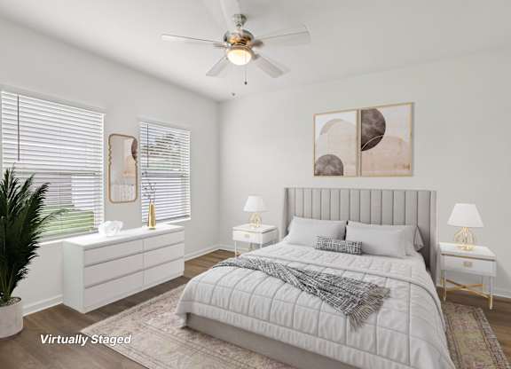 A bedroom with a large bed, a ceiling fan, and a potted plant.