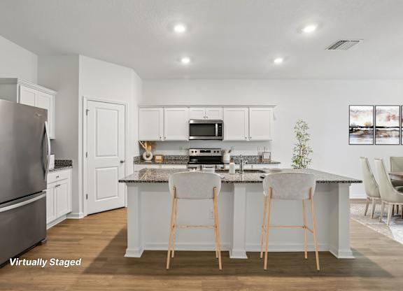 A kitchen with white cabinets and a stainless steel refrigerator.