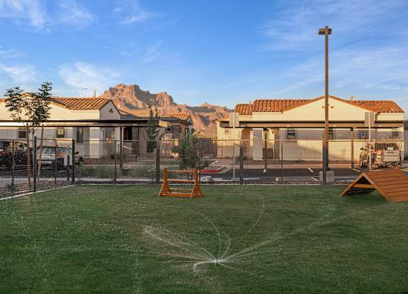 A playground with a sprinkler system in the middle of the grassy area.