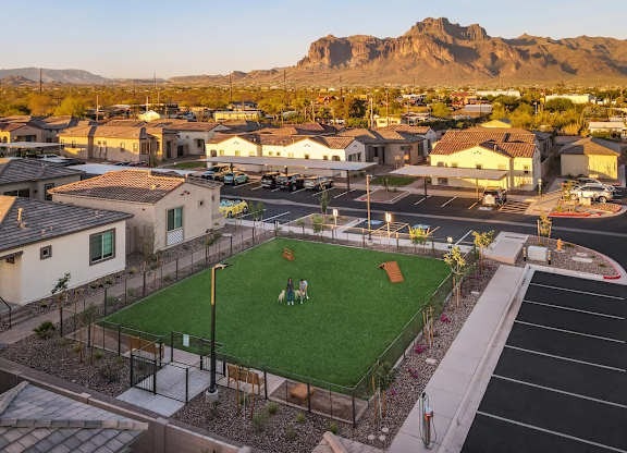 A park with a green lawn and a baseball diamond is surrounded by houses.
