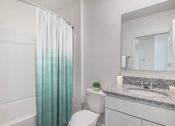 A white bathroom with a toilet, sink, and shower curtain.