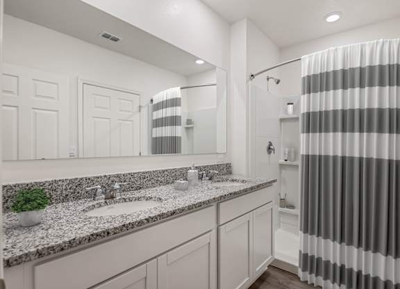 A bathroom with a striped shower curtain and a marble countertop.