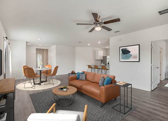A living room with a brown couch and a ceiling fan.