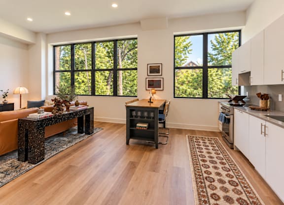 A modern kitchen with a wooden floor and a large window.