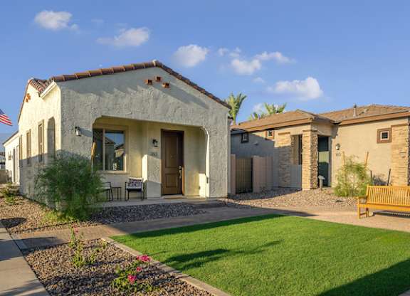 the exterior of a house with a lawn and a bench