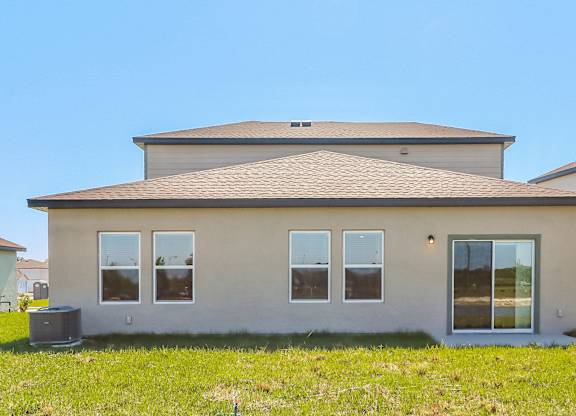 A house with a grey roof and beige walls with a window on the right side.