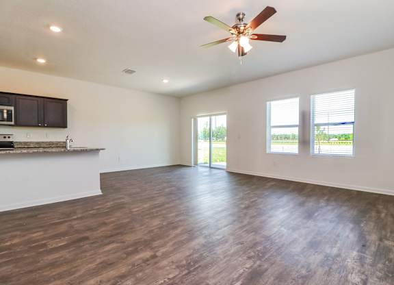A spacious room with a ceiling fan and wooden flooring.