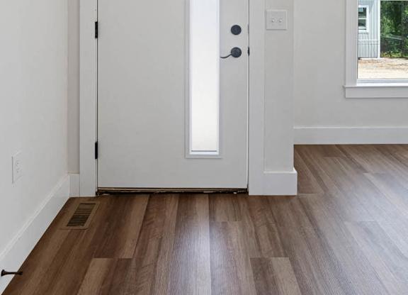 A white door with a black handle is in a room with wooden floors.