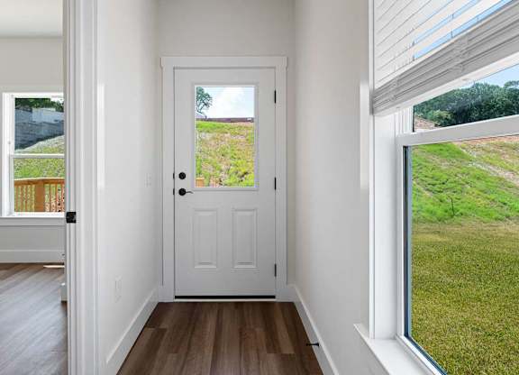 A white door is in a room with a window on the right.