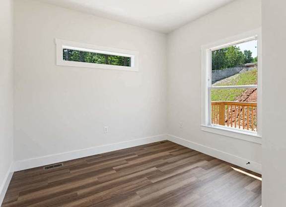 A room with a window showing a view of a green landscape.